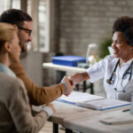 Médica cumprimentando casal durante atendimento para contratação de plano de saúde individual em São Paulo.